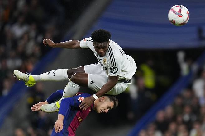 Real Madrid's Aurelien Tchouameni jumps for a header on top of Barcelona's Marc Casado during a Spanish La Liga soccer match between Real Madrid and Barcelona at the Santiago Bernabeu stadium in Madrid, Spain, Saturday, Oct. 26, 2024. (AP Photo/Manu Fernandez) <저작권자(c) 연합뉴스, 무단 전재-재배포, AI 학습 및 활용 금지>