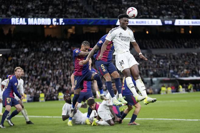 Real Madrid's Aurelien Tchouameni jumps for the ball against Barcelona's Inigo Martinez during a Spanish La Liga soccer match between Real Madrid and Barcelona at the Santiago Bernabeu stadium in Madrid, Spain, Saturday, Oct. 26, 2024. (AP Photo/Bernat Armangue)<저작권자(c) 연합뉴스, 무단 전재-재배포, AI 학습 및 활용 금지>