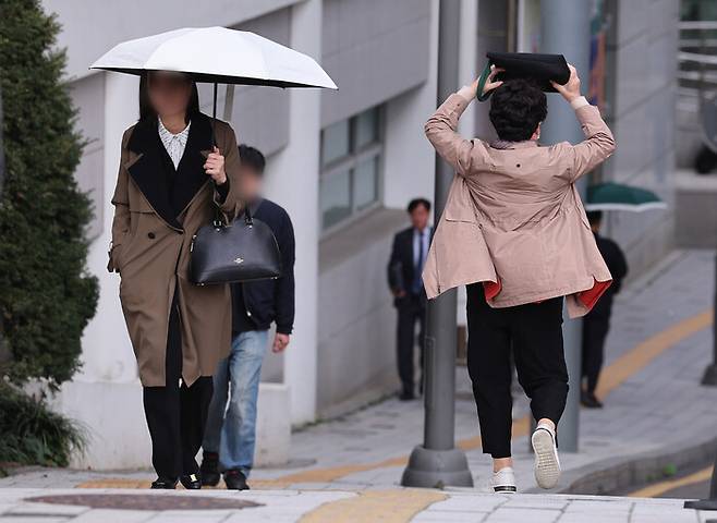 흐린 날씨를 보인 지난달 29일 오전 서울 시내 한 대학병원에서 비가 내리자 한 시민이 가방으로 머리를 가리고 뛰고 있다. 연합뉴스