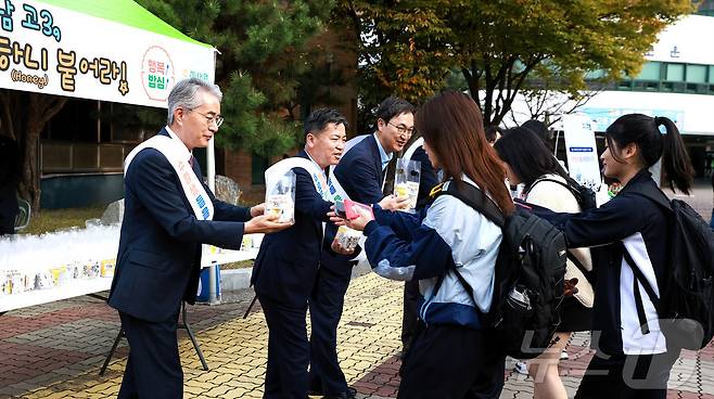 5일 창원용호고등학교에서 박종훈 경남교육감(왼쪽)과 조근수 경남농협 본부장(가운데)이 수능을 앞둔 고등학교 3학년 학생들에게 경남 쌀로 만든 꿀백설기와 식혜를 전하며 응원하고 있다.(경남농협 제공)