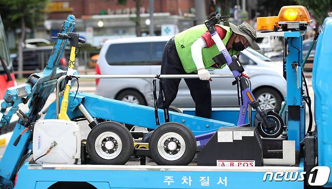 서울 송파구 가락시장역 인근에서 송파구청 관계자들이 불법 주·정차 전동킥보드를 단속해 견인하는 모습. /뉴스1 ⓒ News1 조태형 기자