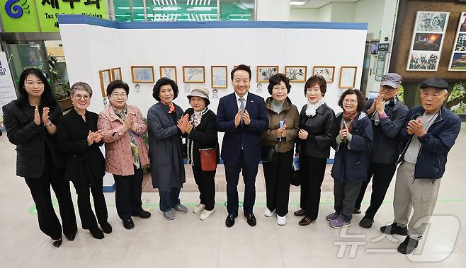 임택 광주 동구청장이 5일 오전 청사 로비에서 진행 중인 '푸른 연필을 보았니' 전시 참여자들과 기념 사진을 찍고 있다. (광주 동구 제공) 2024.11.5/뉴스1