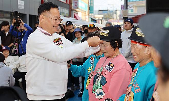 지난 2일 칠곡군에서 열린 쩜오골목축제의 특별행사인 쇼미더할머니 대회에서 우승한 수니와칠공주 할머니에게 김재욱 군수가 모자를 씌어주고 있다. 칠곡군 제공