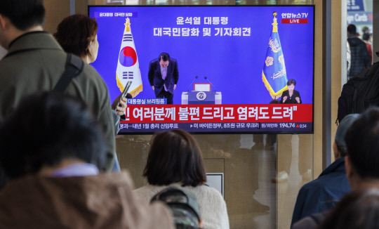 7일 시민들이 서울 중구 서울역에서 텔레비전 생중계되는 윤석열 대통령의 대국민 담화·회견 중 윤 대통령이 고개숙여 사과하는 모습을 지켜보고 있다. 연합뉴스