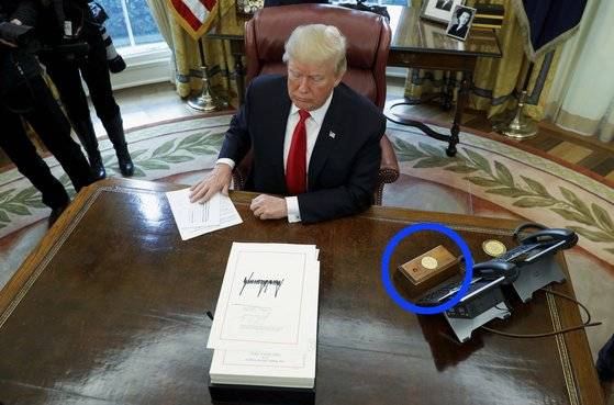 2017년 12월 도널드 트럼프 미국 대통령이 백악관 집무실에서 의회에서 통과된 법안에 대해 서명하고 있다. 파란색 원 안에 있는 빨간 버튼이 이른바 콜라를 요청하는 '코크 버튼'이다. 로이터=연합뉴스