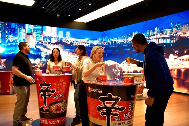뉴욕한국문화원 청사 1층에서 한강을 주제로 한 미디어월을 배경으로 현지 소비자들이 신라면을 먹고 있다.(농심 제공)