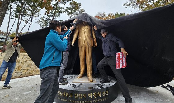 10일 오후 경북 경산시 영남대학교에서 영남대 민주동문회원들이 대학 내 설치된 박정희 동상에 검은 천을 두르고 있다.연합뉴스