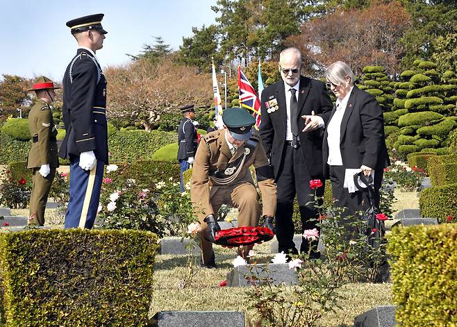 Sgt. Donald Northey's son Michael Northey, second from right, stands in front of his father's grave at the United Nations Memorial Cemetery in Busan as a member of the Gloucestershire Regiment lays a wreath of red poppies on his rededicated headstone. His wife Linda Northey stands next to him on the right. [PARK SANG-MOON]