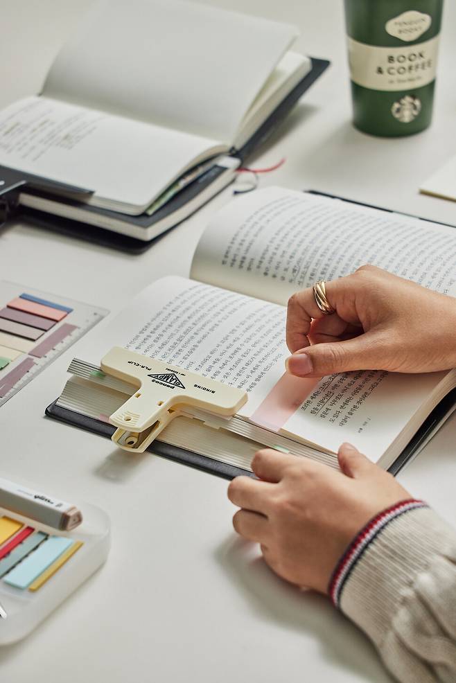 지난 3일 서울 송파구 집에서 유튜버 성시우(필명·30)씨가 북집게와 개인적으로 마음에 드는 문장에 붙이는 붉은 인덱스 등 ‘독서템’을 사용하며 책을 읽고 있다. 윤동길 스튜디오 어댑터 실장