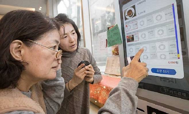 한 어르신이 키오스크 이용에 어려움을 겪다 주변 사람의 도움을 받아 커피를 주문하고 있다. [헤럴드DB}