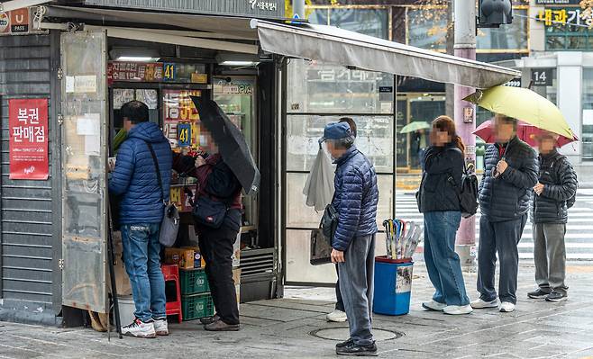 지난 14일 서울 종로3가역 인근 복권 판매점 앞에 구매 대기줄이 늘어서 있다. 혹시 모를 어떤 기대감이 빗방울을 견디게 한다. /임화승 영상미디어 기자