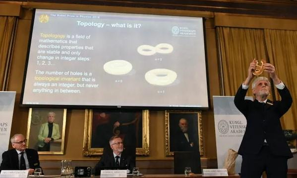 토르스 한스 한손(오른쪽) 노벨위원회 위원이 2016년 10월, 프레츨을 들고 노벨물리학상 수상자들이 연구에 활용한 위상학의 개념을 설명하고 있다. 스톡홀름=AFP 연합뉴스