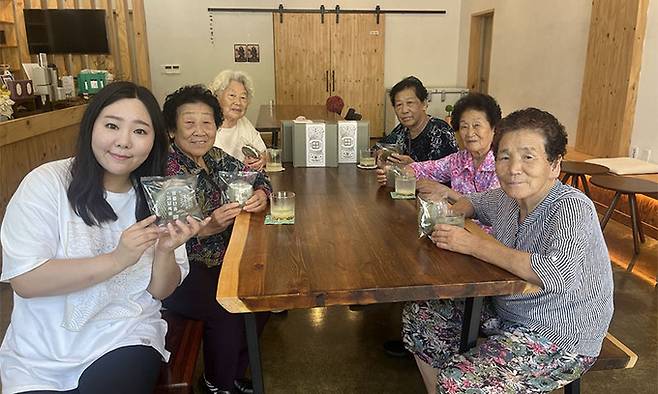 한은경 ‘위로약방’ 대표가 강원 영월군 위로약방에서 함께 일하는 할머니들과 대표 메뉴인 ‘영월 쑥쉘’을 들어 보이고 있다. 한은경 대표 제공
