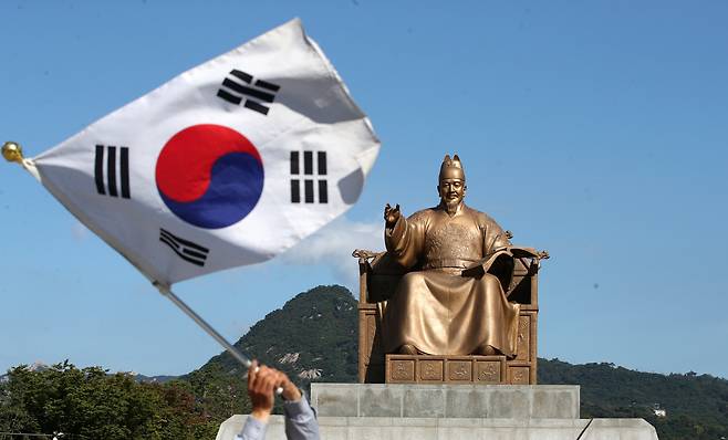 서울 세종대로 광화문광장 세종대왕 동상 앞에서 한 시민이 태극기를 흔들고 있다. /뉴스1