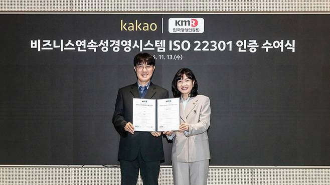 카카오는 지난 13일 경기도 성남시 카카오 판교 아지트에서 ISO 22301 인증서 수여식을 진행했다. 고우찬 카카오 인프라기술 성과리더(왼쪽)와 황은주 한국경영인증원(KMR) 대표이사가 협약서를 들어보이고 있다. 〈자료 카카오〉