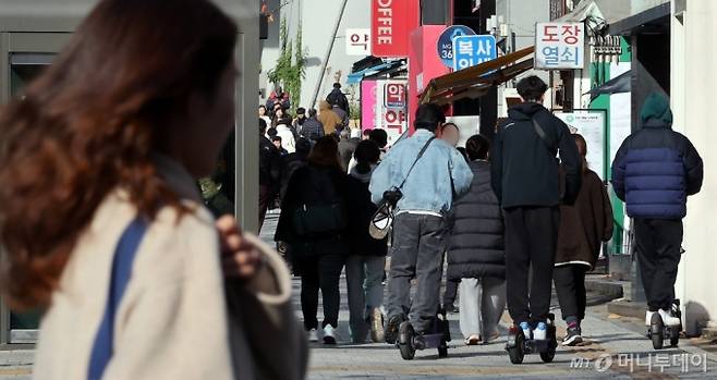 (서울=뉴스1) 이동해 기자 = 19일 서울 시내에서 외국인 관광객들이 전동킥보드를 타고 있다.  19일 업계에 따르면 경찰청은 늦어도 내년 1월까지 유관기관 단체와 협의해 전동킥보드 등 개인형 이동장치(PM) 전용 운전면허 신설과 관련한 합리적 안을 도출할 계획이라고 전했다. 현재 도로교통법상 공유 전동킥보드는 제2종 원동기장치자전거 면허 또는 그 이상(제2종 소형·보통면허, 제1종 보통면허 등)의 운전면허 소지자만 이용할 수 있다. 면허 취득 방식으로는 세 가지가 거론된다. 학과시험(필기시험)만 치르거나, 학과와 기능시험(실습시험)을 함께 치르거나, 온라인 교육만 이수하는 방안 등이 있다. 2024.11.19/뉴스1  Copyright (C) 뉴스1. All rights reserved. 무단 전재 및 재배포,  AI학습 이용 금지. /사진=(서울=뉴스1) 이동해 기자