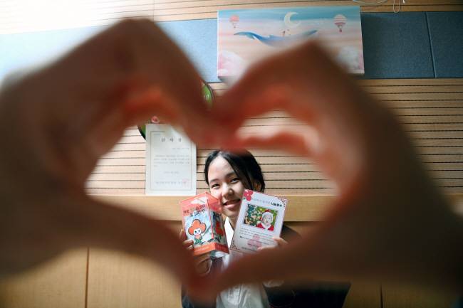 2009년 ‘돌 기부’를 시작으로 15년간 기부를 해온 ‘모태 기부자’ 현송(15) 양이 지난 4일 경북 김천시청에서 부모님이 만든 ‘손 하트’ 사이로 사회복지공동모금회(사랑의열매) 나눔 증서와 기부 저금통을 보이며 웃고 있다. 윤성호 기자