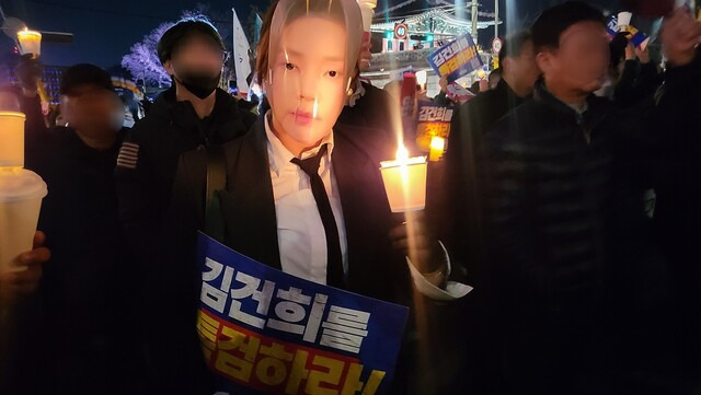 ‘거부권을 거부하는 전국비상행동’이 주최한 23일 오후 ‘윤석열을 거부한다 2차 시민행진\'에 김건희 여사 가면을 쓴 참가자가 촛불을 들어 보이고 있다. 이지혜 기자