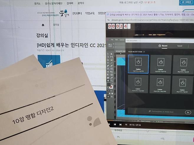 들고 있는 교육 자료 뒤에 강의 영상이 보인다.
