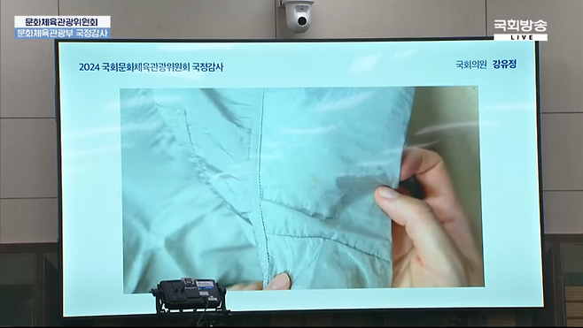 위버스에서 판매한 팔쪽 부분이 이염된 굿즈, 2024년 문화체육관광부 국정감사 생중계 . NATA 국회방송 유튜브 갈무리