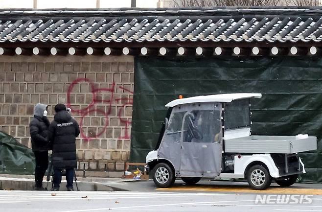 [서울=뉴시스] 김금보 기자 = 문화재청 궁능유적본부 직원들이 지난해 12월16일 오전 서울 종로구 국립고궁박물관 방향 경복궁 서편에서 스프레이 낙서로 훼손된 담벼락을 천으로 덮고 있다. 2023.12.16. kgb@newsis.com