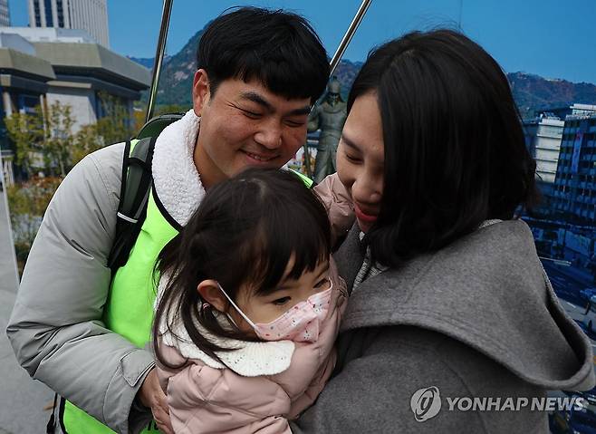 한 자리에 모인 가족 (서울=연합뉴스) 윤동진 기자 = 국내에는 치료법이 없는 희귀병을 앓고 있는 네 살 딸의 치료비용을 위해 전국 곳곳을 돌며 후원을 요청하고 있는 전요셉 씨가 29일 오후 서울 광화문광장에 도착, 부인 이상아 씨, 딸 사랑이와 함께 소감을 밝히고 있다. 2024.11.29 mon@yna.co.kr