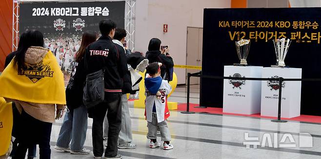 [광주=뉴시스] 변재훈 기자 = 프로야구 KIA타이거즈 팬들이 30일 오후 광주 서구 김대중컨벤션센터에서 열리는 'KIA 타이거즈 V12 팬 페스트' 행사에 앞서 올 시즌 정규시즌·한국시리즈 우승 트로피 앞에서 기념 촬영을 하고 있다. 타이거즈의 올 시즌 통합우승을 축하하기 위한 이날 행사에는 KIA타이거즈 선수단과 코칭스태프, 팬 6000여 명이 참석한다. 2024.11.30. wisdom21@newsis.com