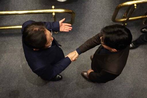 윤석열 대통령이 비상계엄령을 발표한 이후인 4일 새벽 서울 여의도 국회 본회의장에서 국민의힘 한동훈 대표와 더불어민주당 이재명 대표가 국회 본회의장에서 만나 악수하고 있다. 뉴시스