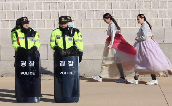 윤석열 대통령이 긴급 비상계엄을 선포한 다음 날인 4일 서울 종로구 경복궁 근처에 배치된 경찰 병력 뒤로 외국인들이 지나가고 있다. 연합뉴스