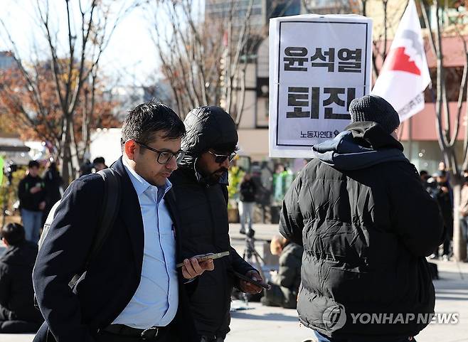 집회 지나치는 외국인 관광객 (서울=연합뉴스) 김성민 기자 = 윤석열 대통령이 긴급 대국민 담화를 통해 비상계엄 해제를 선언한 4일 오전 서울 종로구 광화문광장에서 한 외국인 관광객이 계엄 반대 집회를 지나치고 있다. 2024.12.4 ksm7976@yna.co.kr