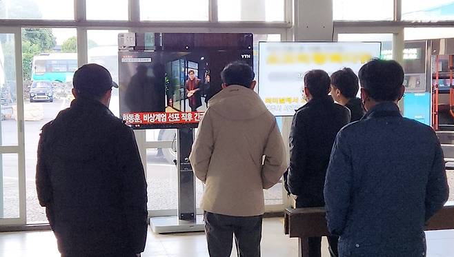 4일 아침, 출근길 시민들이 비상계엄을 다룬 뉴스를 시청하고 있다.