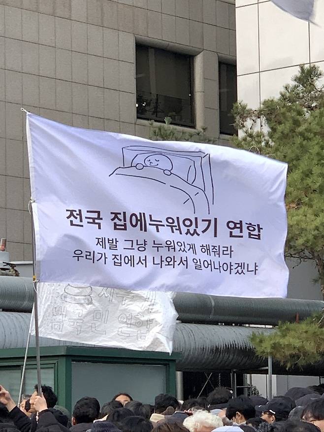 ‘전국 집에누워있기 연합’ 깃발이 7일 오후 서울 여의도 국회 앞 윤석열 대통령 탄핵 촉구 집회 현장에서 휘날리고 있다. 온라인 커뮤니티 더쿠 사진 갈무리