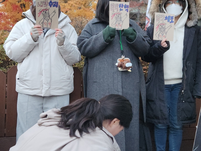 7일 오후 서울 여의도 국회의사당 앞에서 열린 윤석열 퇴진 집회. 집회에 참석한 젊은 시민들이 '내란수괴' '즉각탄핵' 등 문구를 적인 팻말을 순수 제작해 들고 있다. 김승연 기자