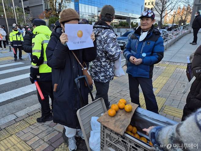 8일 오후 윤석열 대통령 탄핵 촉구 촛불집회가 진행된 서울 여의도 국회의사당 근처에서 한 시민이 '귤 무료 나눔'을 하고 있다. /사진=박진호 기자