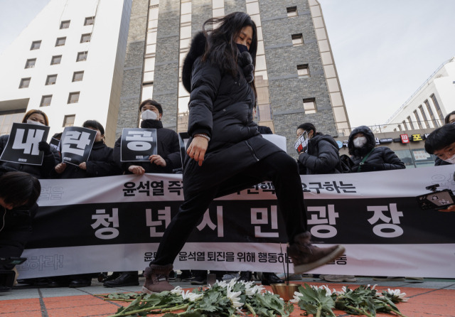 ▲11일 오전 서울 여의도 국민의힘 당사 앞에서 윤석열 퇴진을 위해 행동하는 청년 일동(윤퇴청)이 주최한 '국민의힘 해체'를 위한 장례식에서 한 참가자가 헌화를 마친 뒤 국화를 발로 밟고 있다. ⓒ연합뉴스