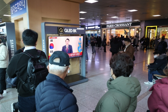 12일 오전 서울역에서 시민들이 윤석열 대통령 담화를 TV로 보고 있다. 2024.12.12 연합뉴스