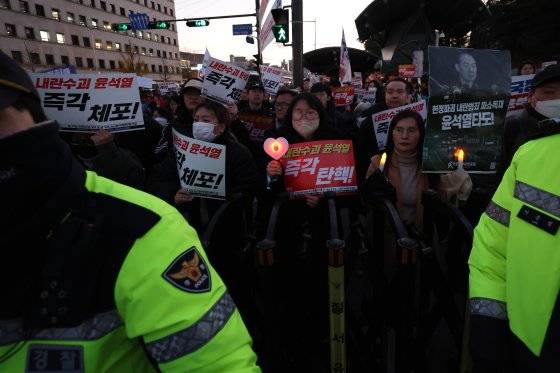 6일 오후 서울 여의도 국회의사당 앞에서 열린 윤석열 대통령의 퇴진 촉구 집회에서 시민들이 손피켓을 들고 정권 퇴진을 촉구하고 있다. 서울청 기동대 소속 경찰들은 "비상계엄이 선포된 이후부터 대형 집회가 이어지면서 제대로 쉬지 못하고 있다"고 말했다. 뉴스1