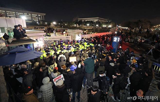 윤석열 대통령의 비상계엄 해제 요구 결의안이 국회 본회의에서 통과된 4일 새벽 서울 여의도 국회 정문 앞에 모인 시민들이 윤 대통령을 규탄하고 있다. //사진=뉴스1