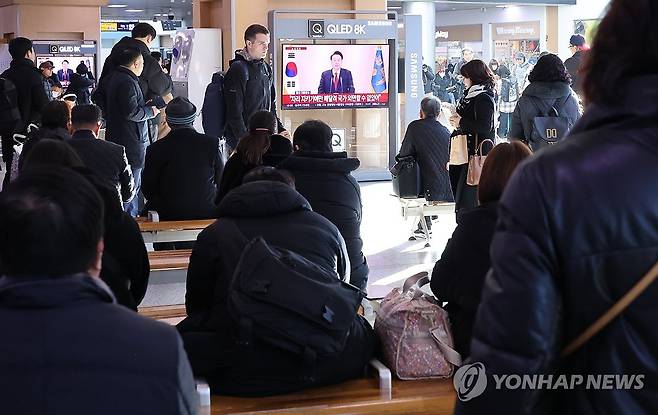 대통령 담화 시청하는 시민들 (서울=연합뉴스) 이진욱 기자 = 12일 오전 서울역에서 시민들이 윤석열 대통령 담화를 TV로 보고 있다. 2024.12.12 cityboy@yna.co.kr