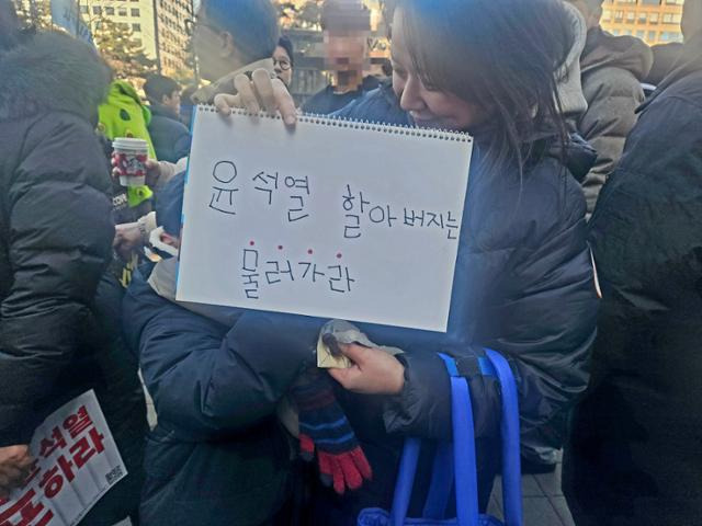 윤 대통령 탄핵을 촉구하는 인파가 국회 앞을 가득 메운 가운데 '윤석열 할아버지는 물러가라'고 적힌 스케치북을 든 7세 아이와 함께 이곳을 찾은 김혜신(38)씨. 김혜지 기자