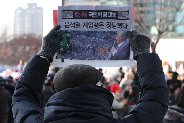 윤석열 대통령에 대한 국회 탄핵소추안 표결일인 14일 서울 세종대로 일대에서 대한민국살리기국민운동본부를 비롯한 보수단체 회원들이 '윤석열 계엄령은 정당했다' 문구가 적힌 전단지를 들고 12·14 광화문 국민혁명대회에 참석하고 있다. 뉴스1