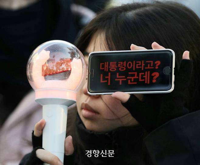 윤석열 대통령에 대한 두 번째 탄핵안 표결을 앞둔 14일 서울 여의도 국회 앞에서 열린 범국민촛불대행진에 참석한 한 시민이 ‘대통령이라고? 너 누군데?’라는 문구를  적은 휴대전화 화면을 들어 보이고 있다. 정효진 기자