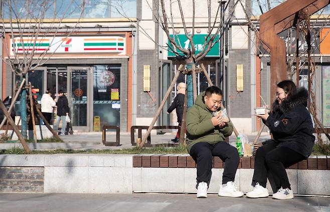 12월9일 젊은 남녀가 베이징 시내 한 편의점 밖 길거리에서 식사를 하고 있다.  이날 발표된 중국 11월 소비자물가지수 증가율은 0.2%로 디플레이션 우려가 커지고 있다.  /EPA 연합뉴스