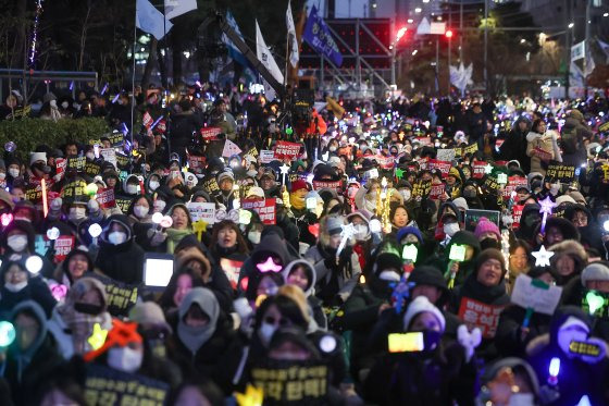 윤석열 대통령에 대한 국회의 2차 탄핵소추안 표결을 하루 앞둔 13일 오후 서울 영등포구 여의도 국회 앞에서 열린 '윤석열 즉각 탄핵 구속 촉구 촛불문화제'에서 참가자들이 응원봉과 손팻말을 들고 있다. 뉴스1