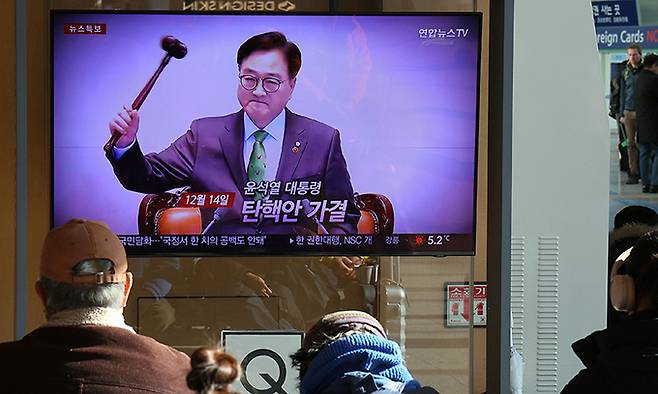 15일 서울역 대합실에서 시민들이 대통령 탄핵소추안 가결 관련 뉴스를 시청하고 있다. 연합뉴스