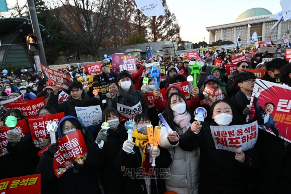 윤석열 대통령 탄핵소추안이 가결된 14일 오후 서울 여의도 국회의사당 앞에 모인 시민들이 피켓을 든 채 환호하고 있다. 오후 5시 기준 200만명(주최 측 추산·비공식 경찰 추산 20만명)이 이 자리에 모였다. 일부 시민들은 서로를 얼싸안고 눈물을 흘리기도 했다.