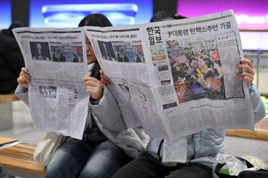 윤석열 대통령 탄핵소추안이 국회에서 가결된 지난 14일 오후 서울역에서 시민들이 한국일보 특별판을 보고 있다.(사진=연합뉴스)