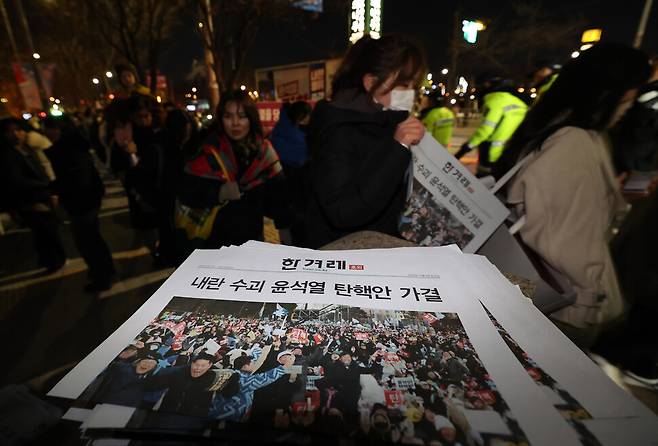 14일 오후 서울 지하철 5호선 여의나루역에서 시민들이 탄핵 가결 소식을 전하는 한겨레 호외를 가져가고 있다. 김태형 기자 xogud555@hani.co.kr