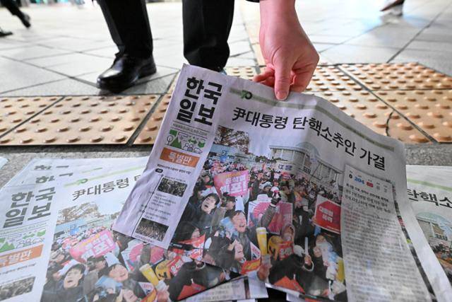 윤석열 대통령 탄핵소추안이 국회에서 통과된 14일 서울 용산구 서울역에서 시민들이 한국일보 특별판(호외)을 가져가고 있다. 박시몬 기자