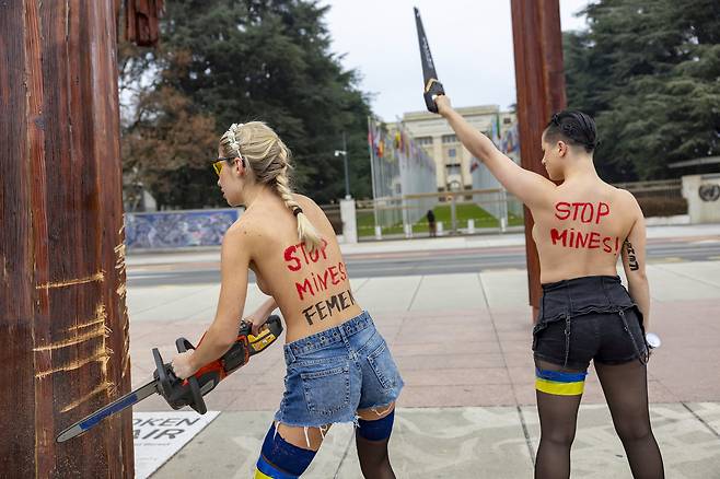 13일(현지시각) 페미니스트 단체 페멘(Femen) 활동가들이 스위스 제네바 유엔 유럽 본부 앞 광장의 '부서진 의자' 기념비 아래에서 우크라이나를 지지하고 러시아의 유엔 추방을 요구하는 시위를 벌이고 있다. /AP 연합뉴스